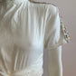 White skater dress with gold and colored yoke on the arms and open back