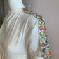 White skater dress with gold and colored yoke on the arms and open back