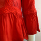 Red blouse with lace on the front and ruffles.